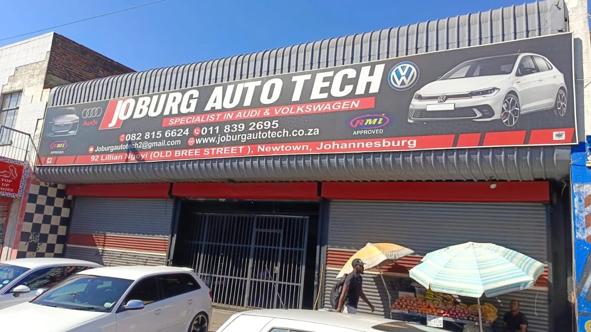Exterior of Joburg Autotech Volkswagen dealership storefront with signage, parked cars, and open garage bay in Johannesburg